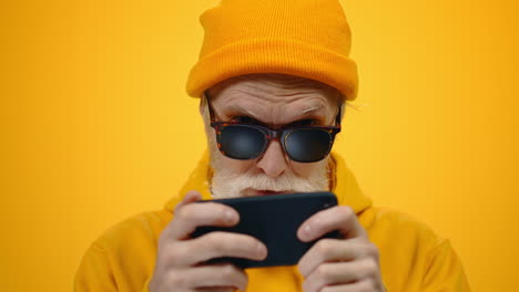 mature man looking to cellphone in studio. focused guy playing online indoors.