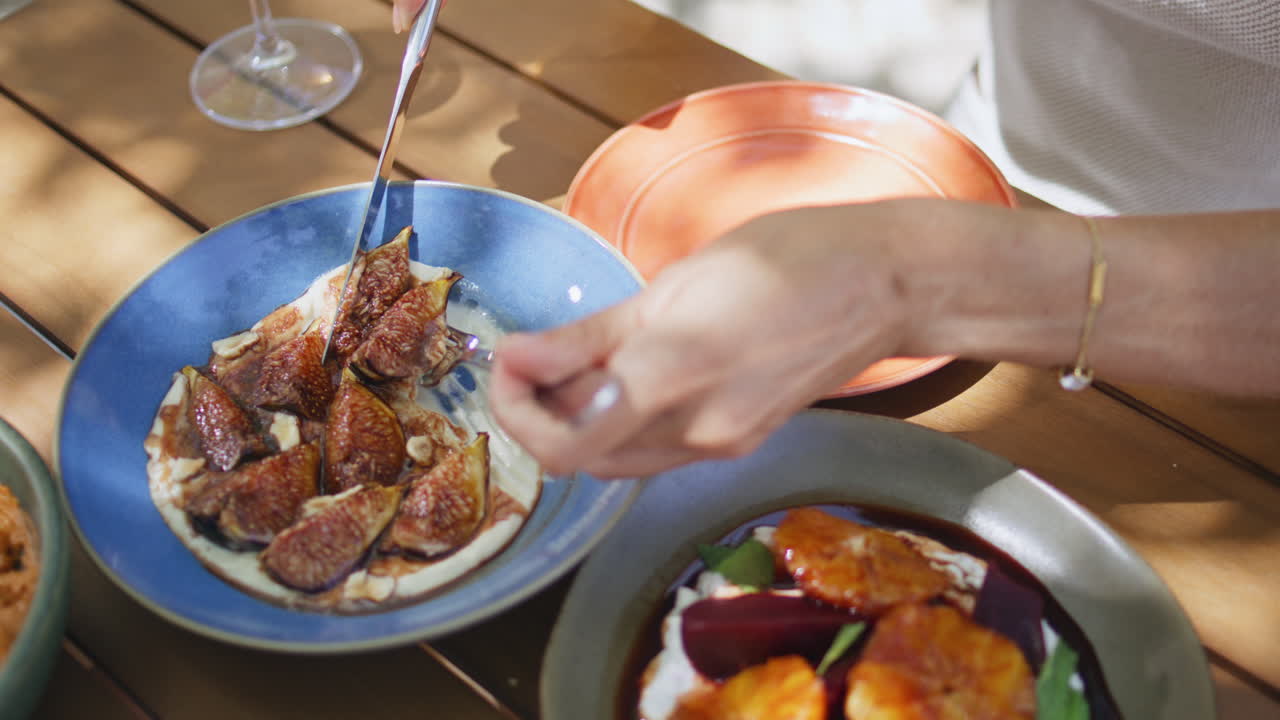 las manos de la dama tomando hummus con higos de un plato azul en un café de primer plano. la mujer comiendo