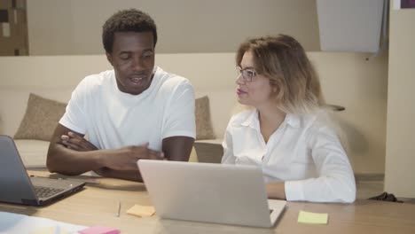 two project managers sitting at table with laptops