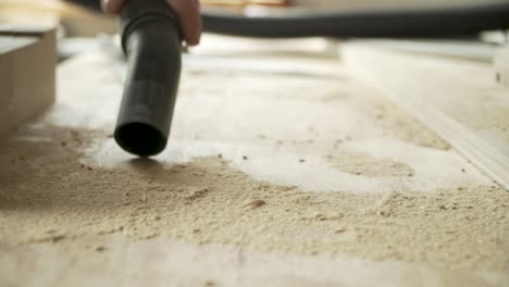 Close-up-male-hand-vacuuming-sawdust-on-a-work-bench,-day-time-static-shot