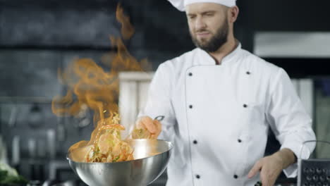 professional chef cooking in pan with fire in slow motion