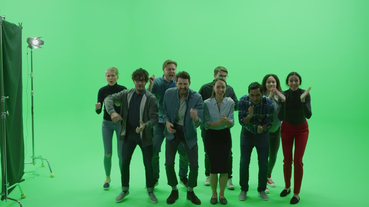 Studio con schermo verde Chroma Key, folla eterogenea di fan multietnici che esultano e applaudono con le mani alzate a un evento sportivo pubblico, concerto, festival, festa. Ripresa frontale a figura intera al rallentatore