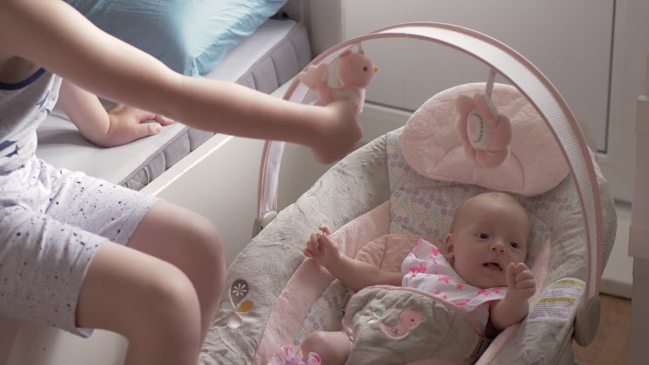 조심스러운 형제는 집에서 아기 여동생을 돌보고 있습니다.