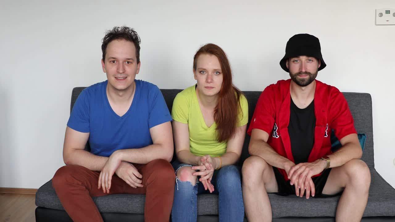Young friends sit on the sofa and cheer over a goal