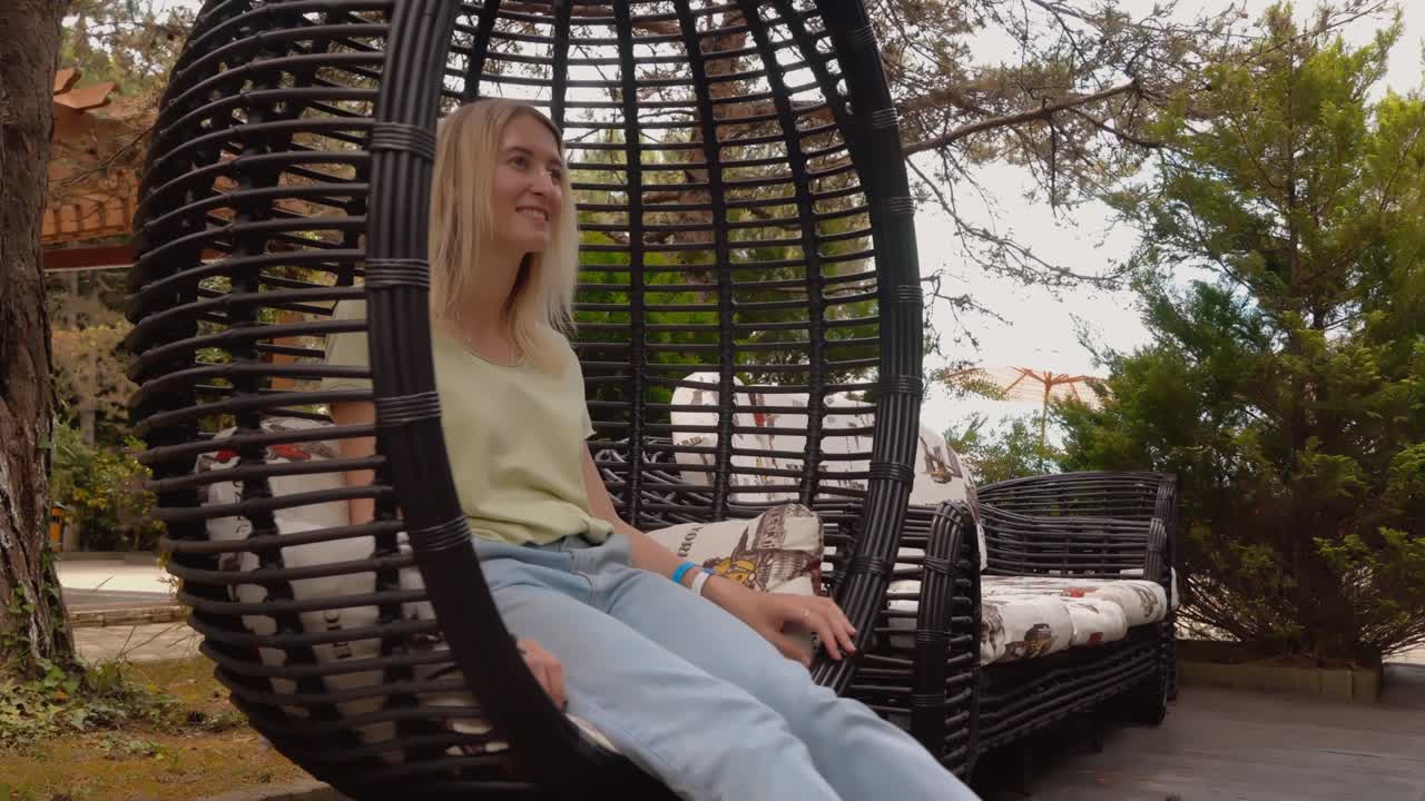 el turista se balancea en rattan de mimbre, cuelga una silla en el parque en el patio