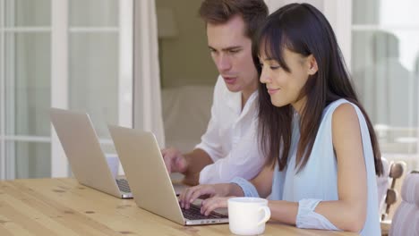 pareja trabajando juntos en computadoras portátiles