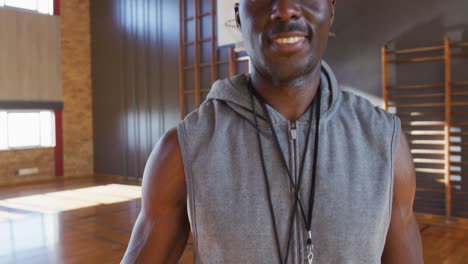 Portrait-of-african-american-male-basketball-coach-holding-ball-smiling