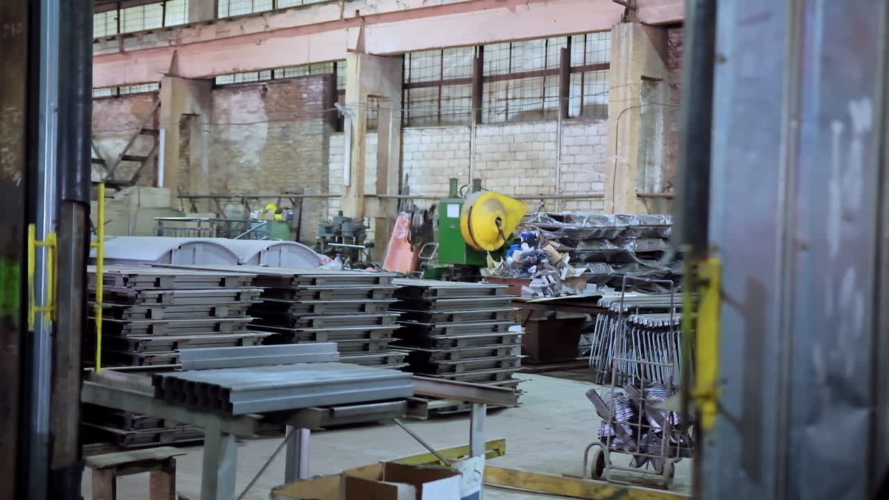 Manufacturing indoors. Male worker in uniform and hard hat working on the industrial materials background inside the plant. Slow motion.