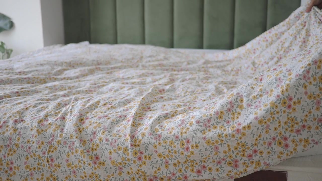 Persona che rifà il letto con un copripiumino a fantasia floreale