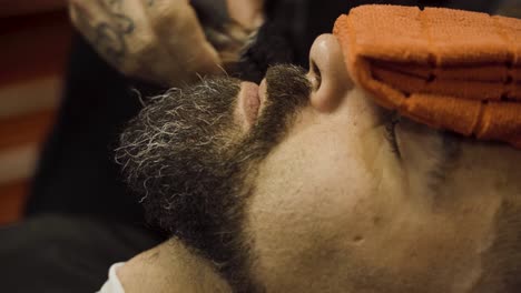 el barbero corta el bigote del cliente con una máquina de afeitar - de cerca