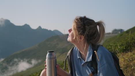 woman enjoying a scenic mountain view with a thermos