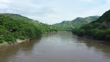 Aerial-view-of-green-colombian-landscape,-green-hills-and-muddy-Magdalena-river