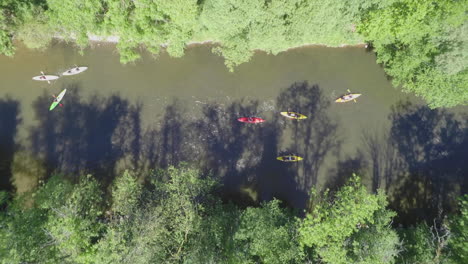 aerial-slomo: topshot of kayaks floating down a river on a sunny day