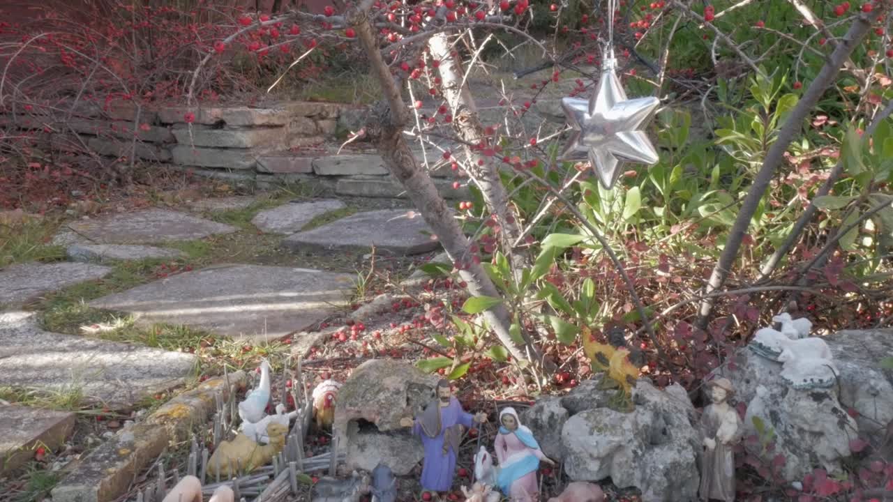 A serene outdoor nativity scene with figurines, a star ornament, and natural elements
