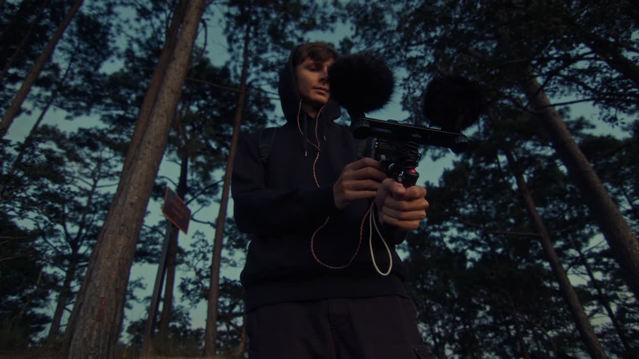 Man holding a microphone in a forest