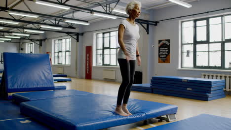 Elderly woman exercising on gymnastics mat in gym