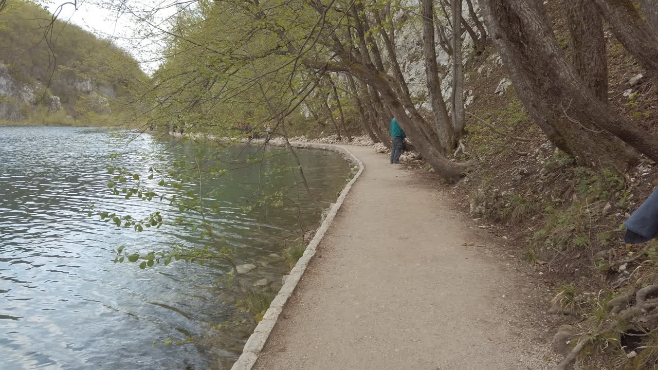 un sendero de madera hecho por el hombre entre un lago azul claro y un acantilado de montaña 2
