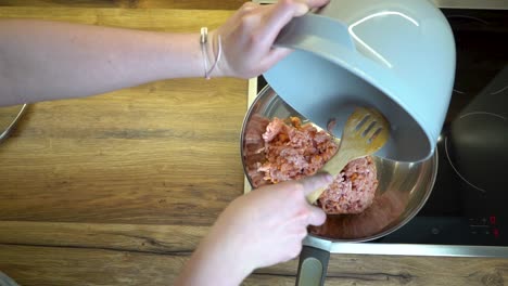 mujer vertiendo carne picada en una sartén con cuchara de madera