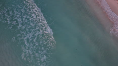 Toma-Aérea-De-Arriba-Hacia-Abajo-De-Olas-En-Un-Océano-Azul-Cristalino-Con-Playa-De-Arena-Blanca-En-Cancún,-México