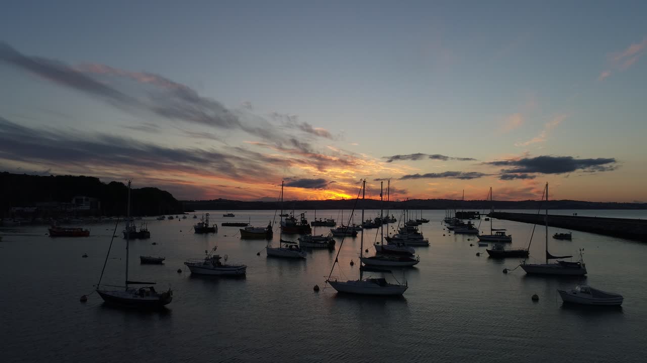 Brixham, Devon, Regno Unito. Tramonto. Volo di drone sopra barche in mare aperto.