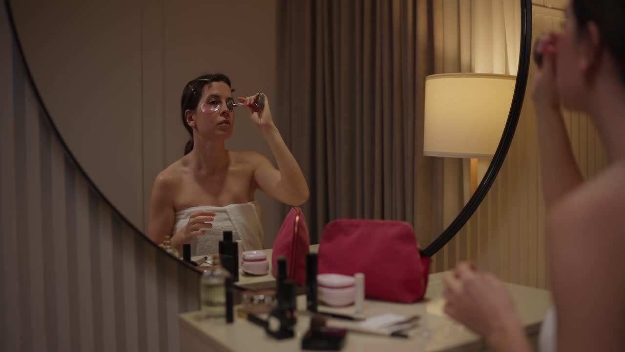 Woman using face roller in mirror
