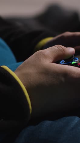 Vertical-Video-Close-Up-Hands-Man-Playing-Video-Game-Controller-Sitting-Sofa-At-Home