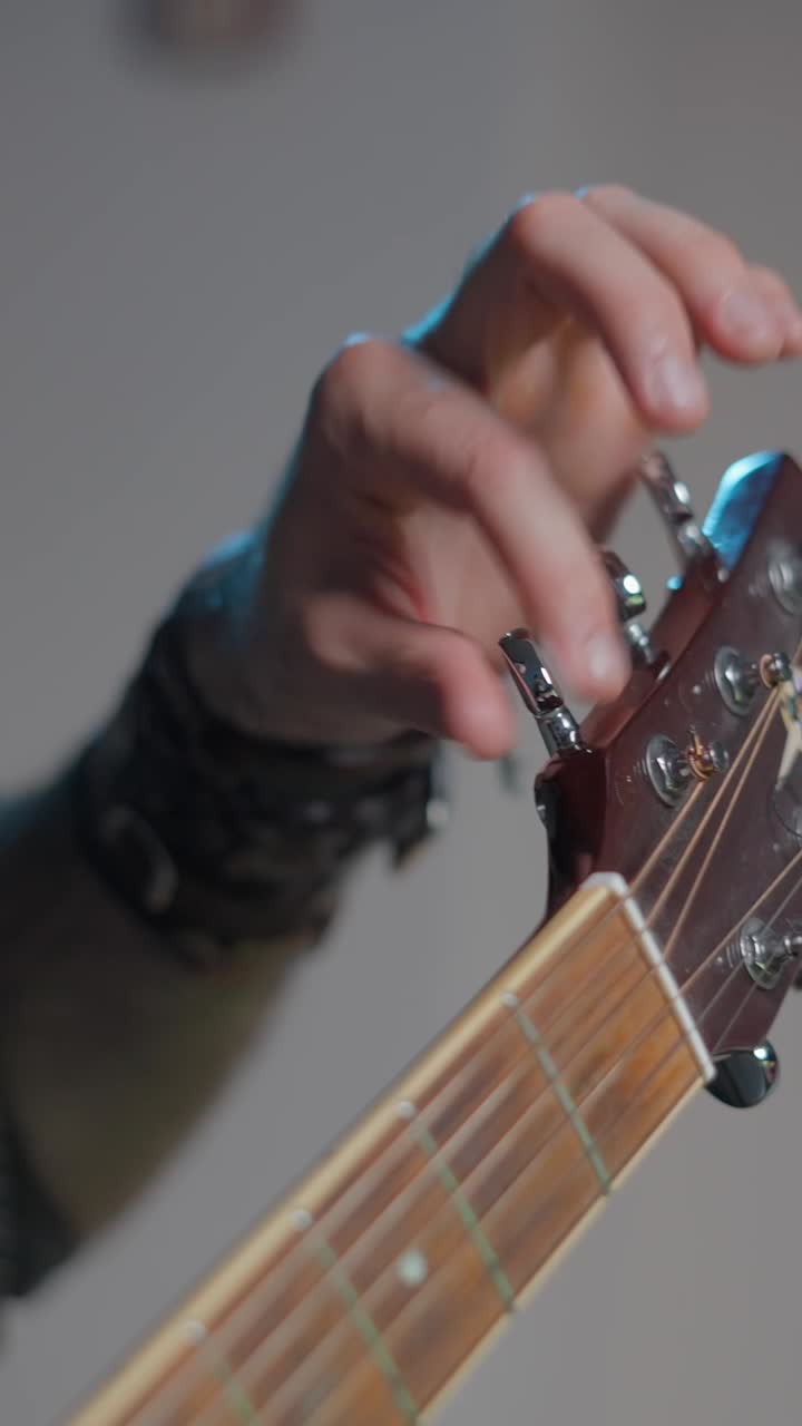 A hand tuning an acoustic guitar