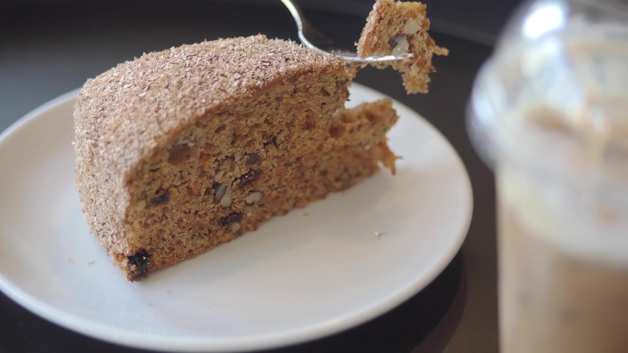 A slice of carrot cake being eaten with a fork