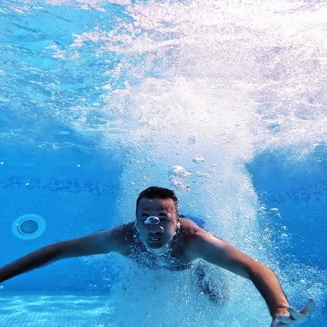 an energetic dive into a swimming pool. handsome young man swimming in pool, underwater view