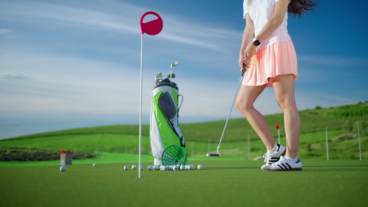 Woman dressed in white and pink playing golf near a cart bag on the course