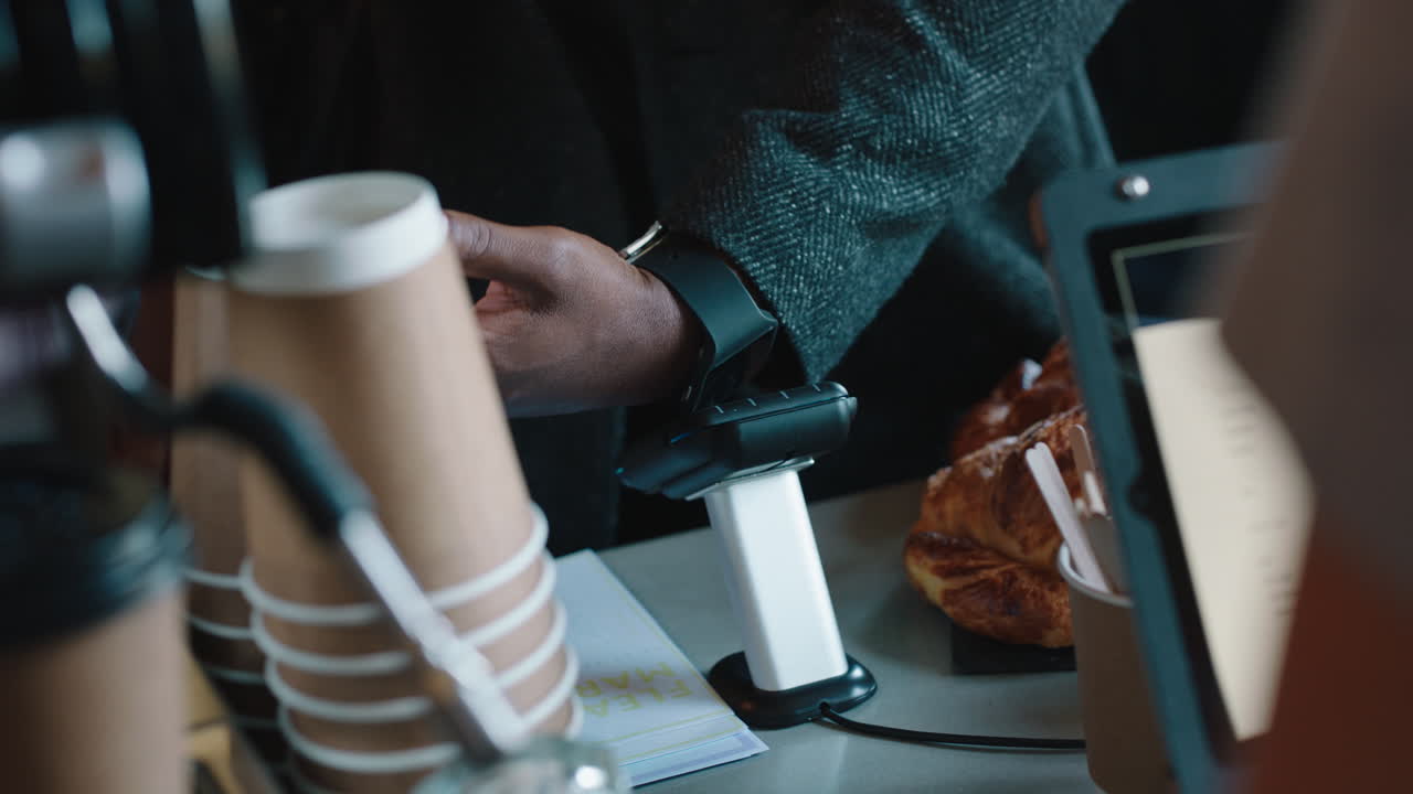 jovem afro-americano fazendo pagamento sem contato usando relógio inteligente transferência de dinheiro móvel comprando café em um café desfrutando do serviço em um restaurante