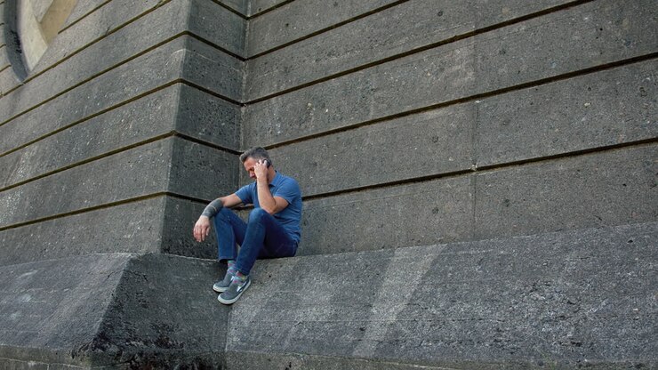 After cell phone call, frustrated man throws phone, park, slow motion