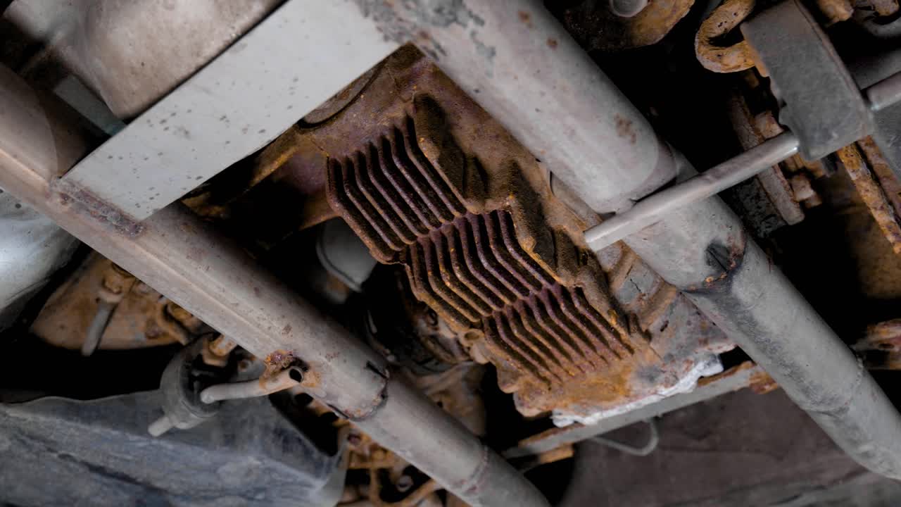 Close up of the underside of a used rusty car. The rear end differential and other suspension parts need maintenence. Rotating movement shot in 4k.