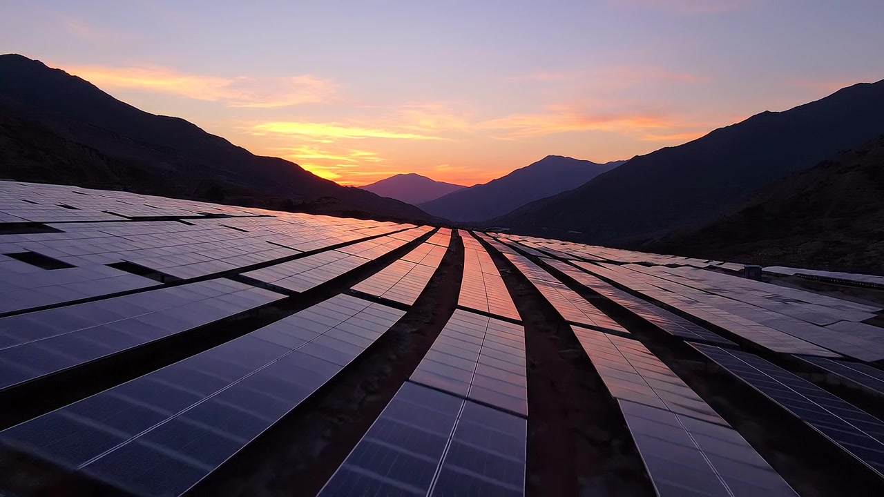 Solcellepark ved solnedgang i et bjergdalslandskab