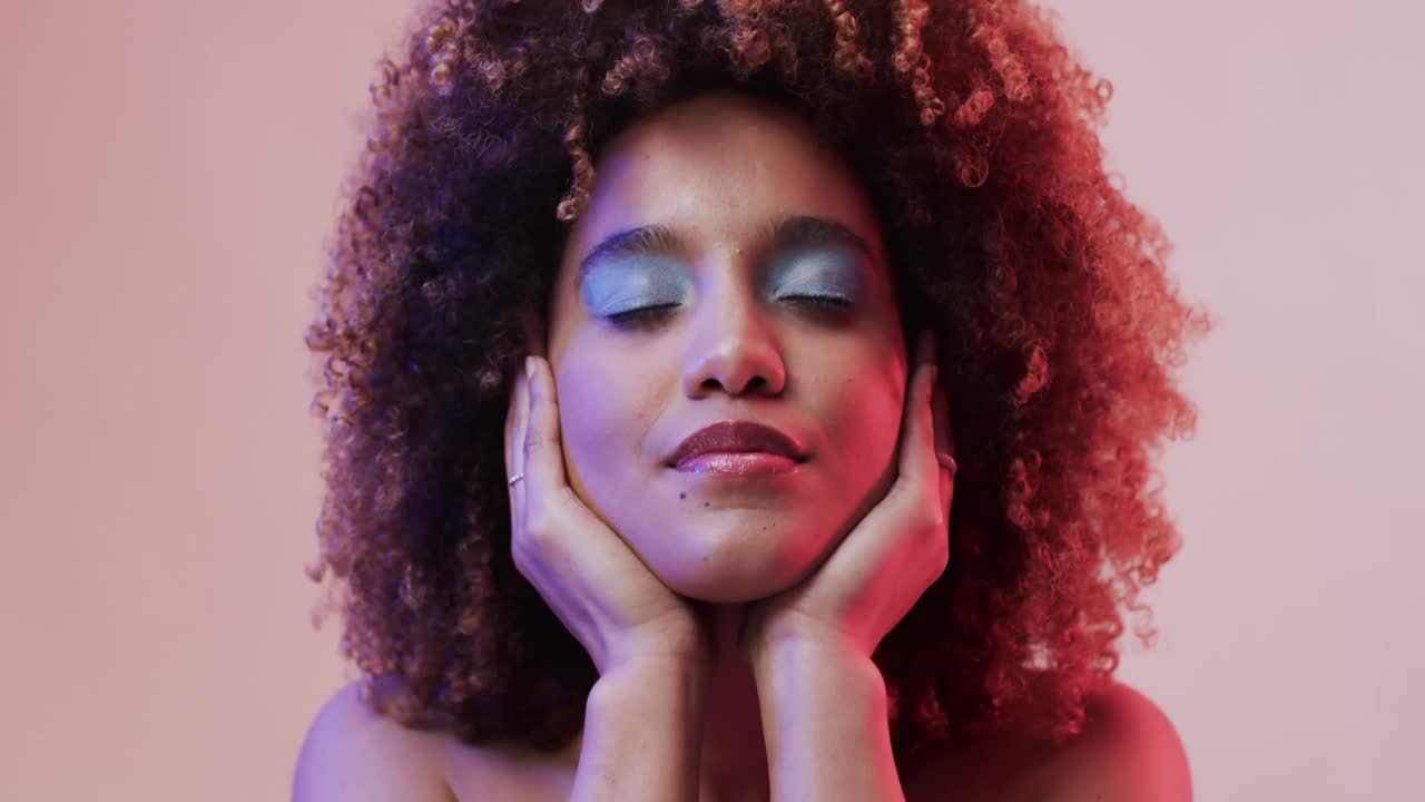 Happy biracial woman with dark hair in blue and pink light, slow motion