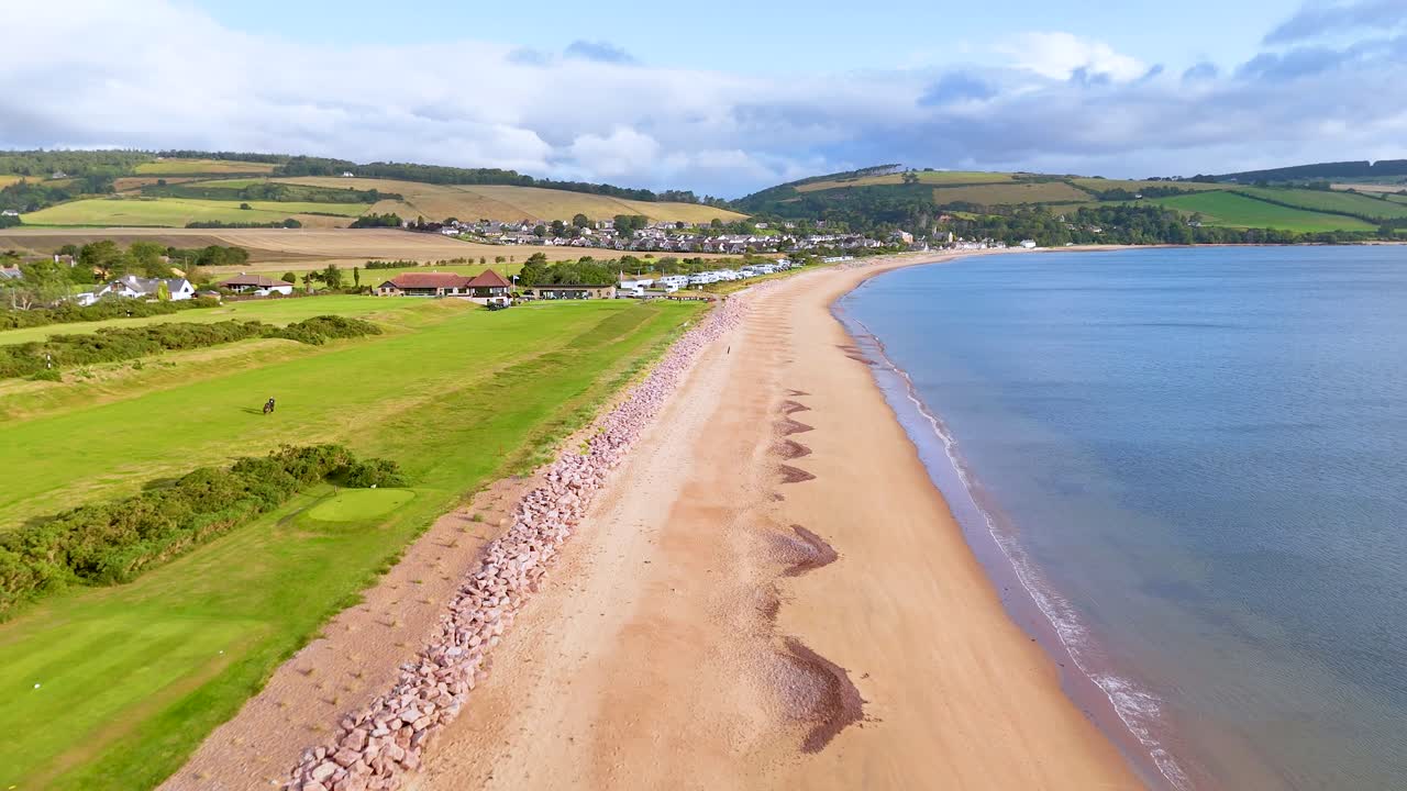 Flygbilder med drönare av Rosemarkie Beach, golfbana och gröna fält en solig dag