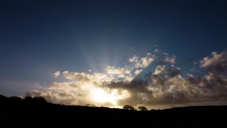 Vista-Aérea-Ascendente-Del-Espectacular-Amanecer-Con-Rayos-De-Luz-A-Través-De-Un-Paisaje-Nuboso-Con-Siluetas-De-árboles---Drone-Shot-Uk-4k