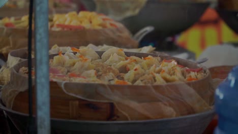 indonesian chef selling asian dimsum food from wooden basket behind a showcase