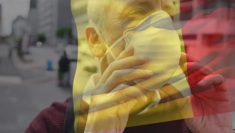 animation of flag of belgium waving over caucasian man wearing face mask in city street