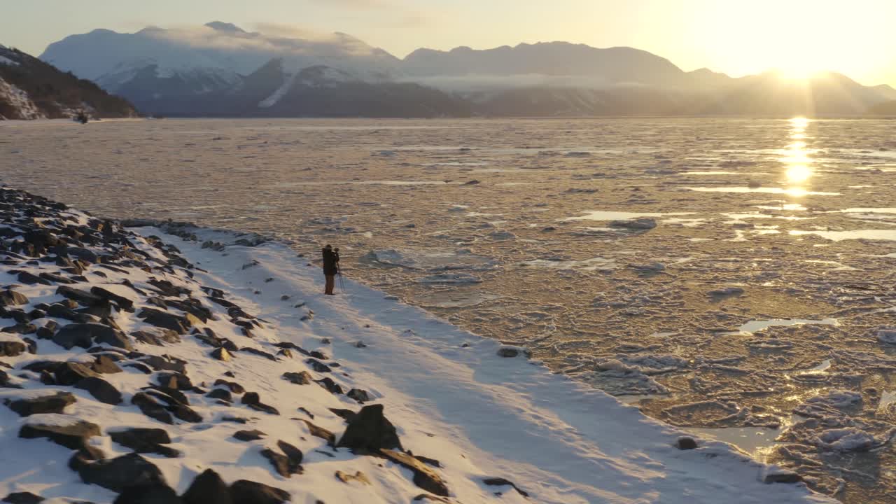 el fotógrafo de aventuras se encuentra afuera en el frío clima de alaska para ver el amanecer