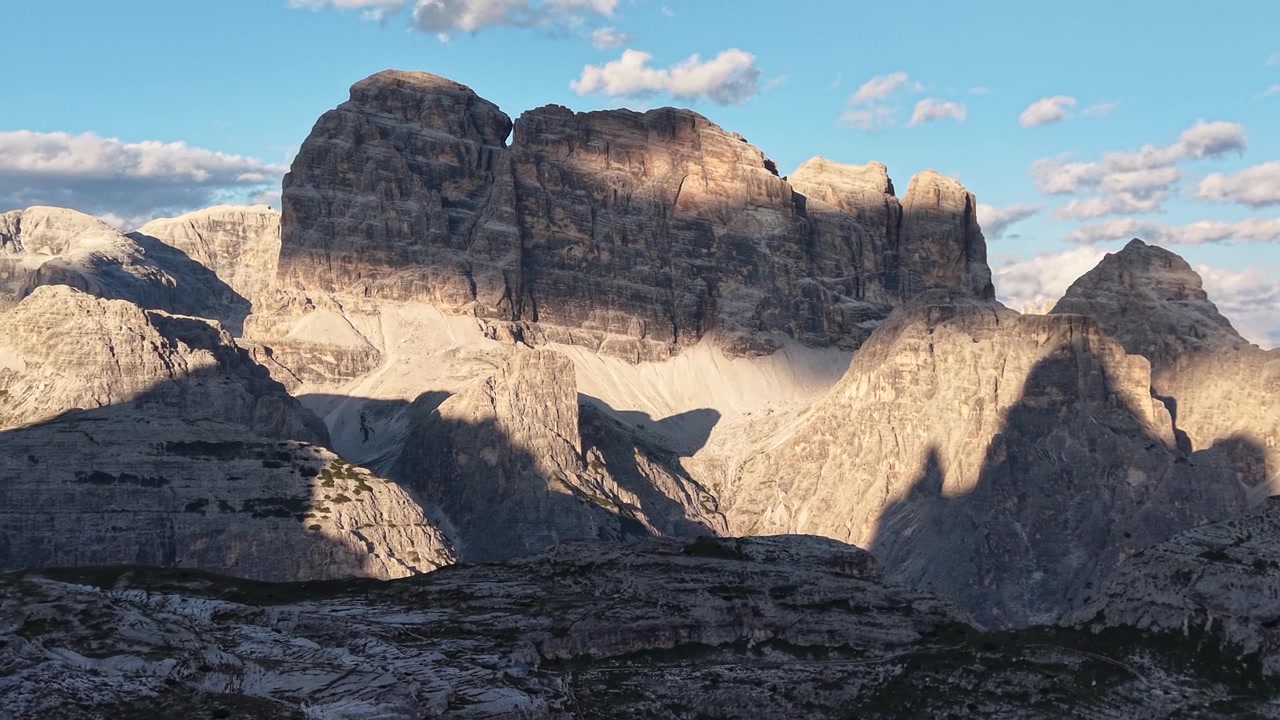 Langsom opadgående droneafsløring af Croda dei Toni oplyst af varmt gyldent time-lys nær Rifugio Lavaredo i Dolomitterne, Italien