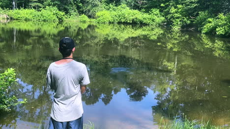 niño adolescente pescando en un estanque en un soleado día de verano
