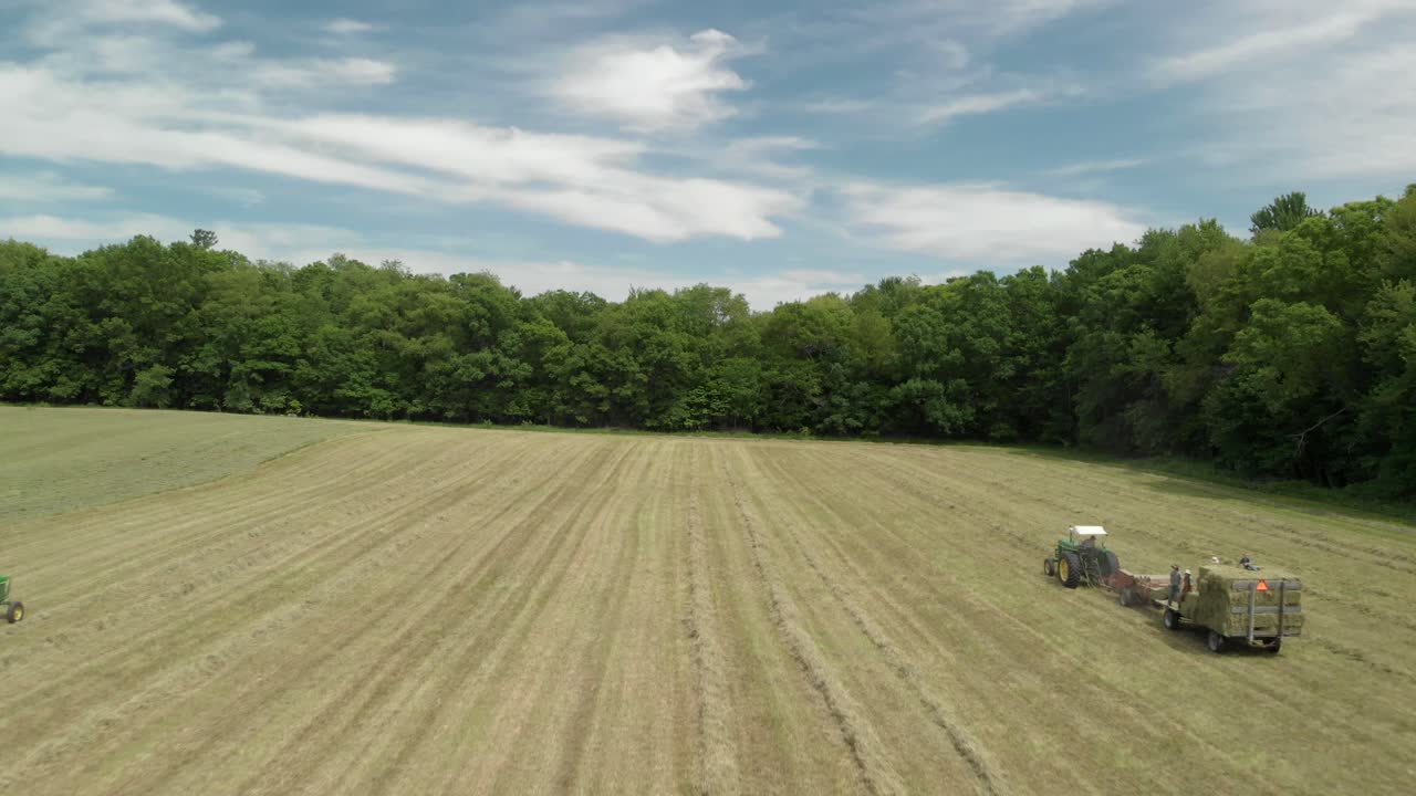 Drohnenaufnahme: Flug über Traktoren bei der Heuernte auf einem Feld