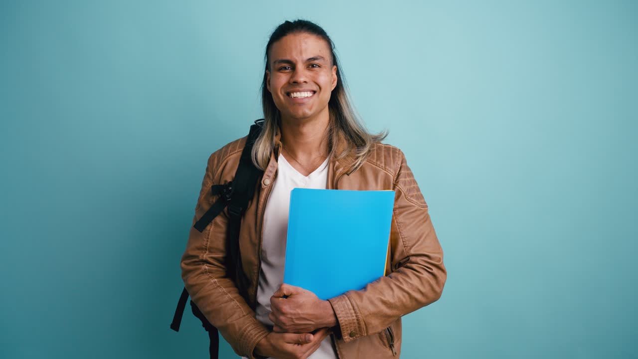 Giovane studente che sorride e tiene una cartella blu.