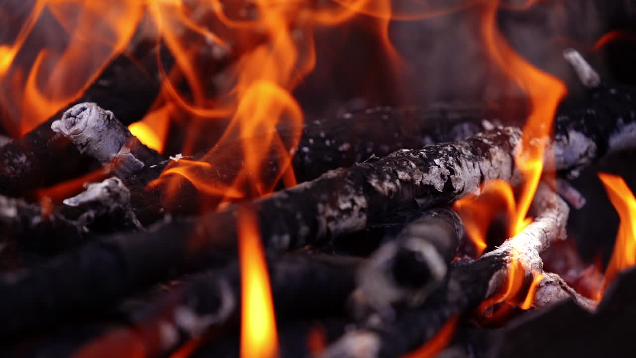 Fiamme di fuoco rosso vivo in una griglia da barbecue, braciere. Falò luminoso con luci vibranti. Legna da barbecue che brucia. Primo piano. Movimento rallentato.