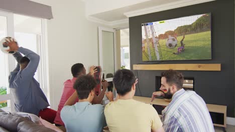 Video-of-diverse-friends-sitting-on-sofa-and-watching-football-on-television-at-home