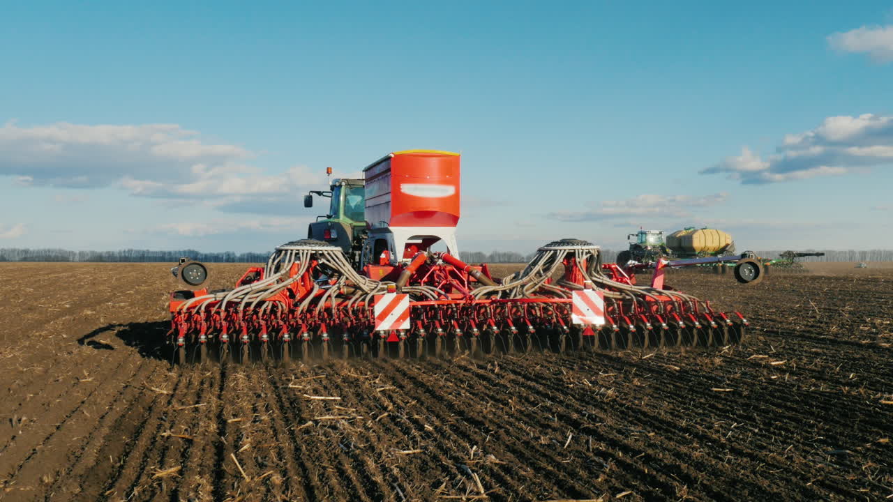 toma de steadicam: dos tractores con sembradoras siembran trigo en el campo a principios de la primavera 1
