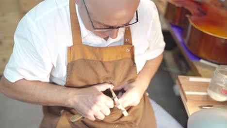 Luthier-with-violin-bridge-in-workshop