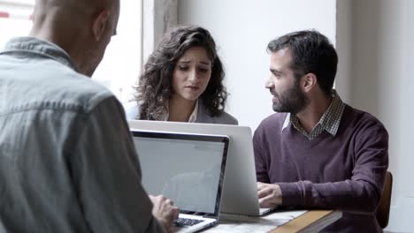 confident employees discussing new project with laptops