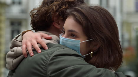 lovely couple in medical masks hugging outdoor. lovers spending time outside.